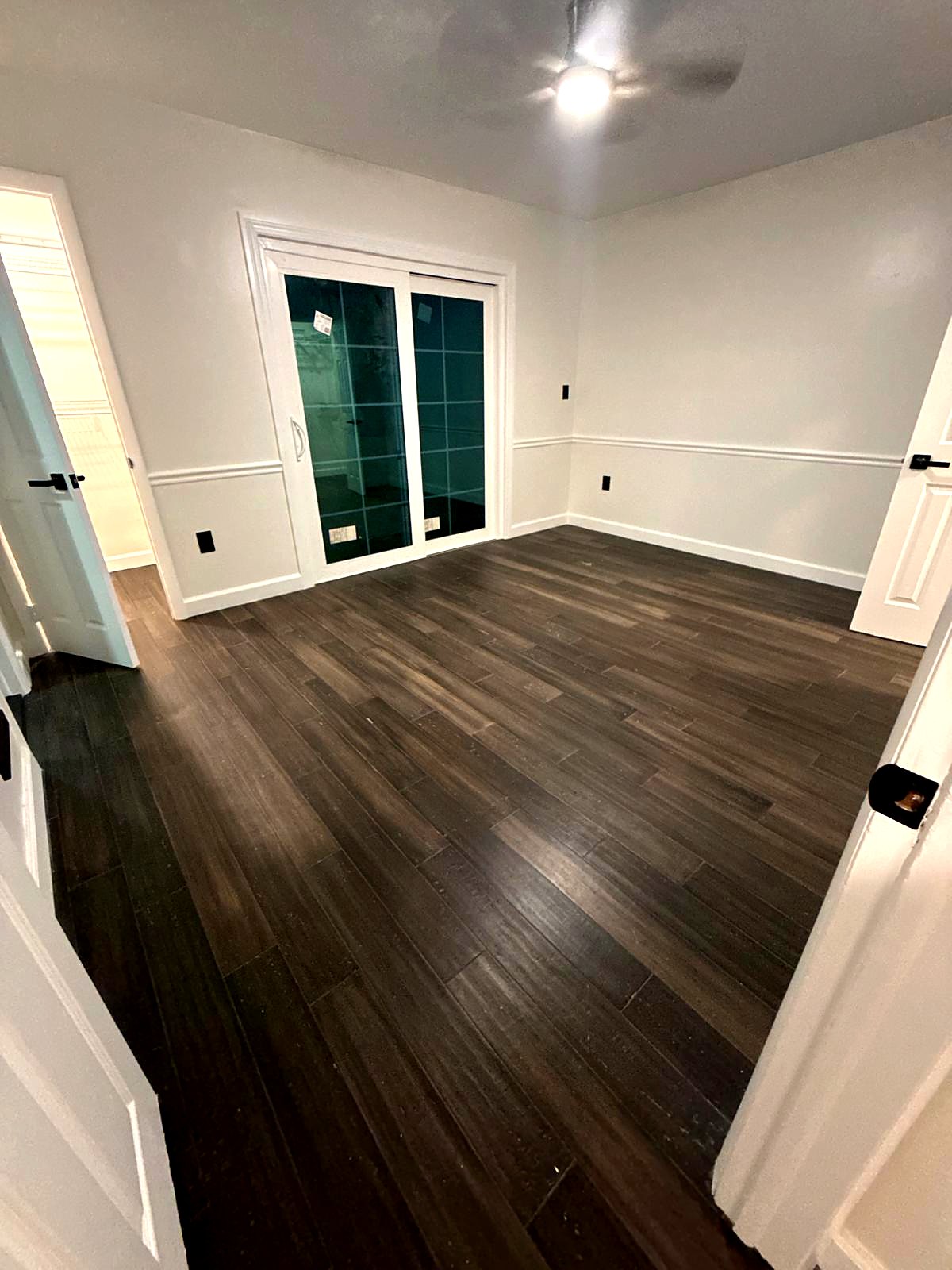 Bedroom with a dark plank floor, chair rail and sliding glass doors
