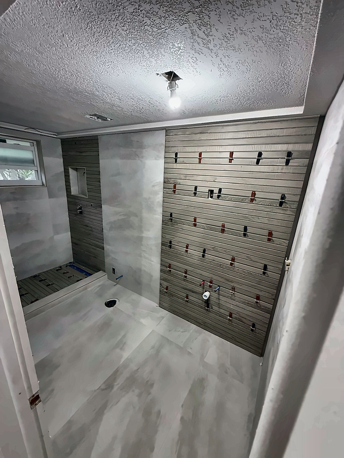 Large-format tile set across the walls with leveling clips at every joint and string lines run