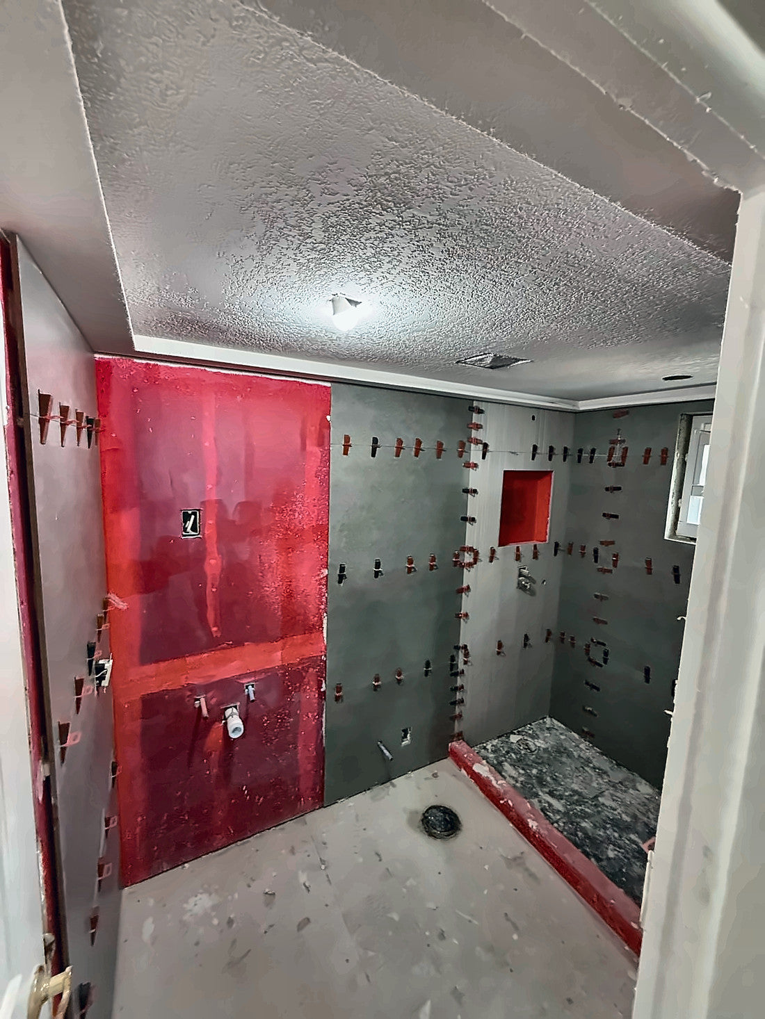 Waterproofing membrane painted red over the board, the curb and the recessed niche