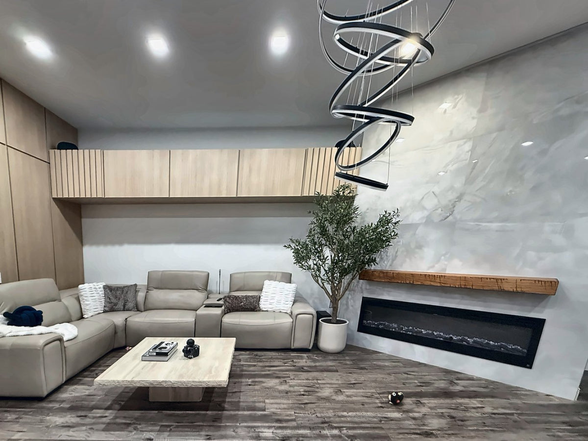 The same wall after renovation: a full-height marble-look plaster slab with a linear fireplace, the original timber mantel reinstalled, and a run of light oak cabinetry with a fluted panel where the soffit used to be