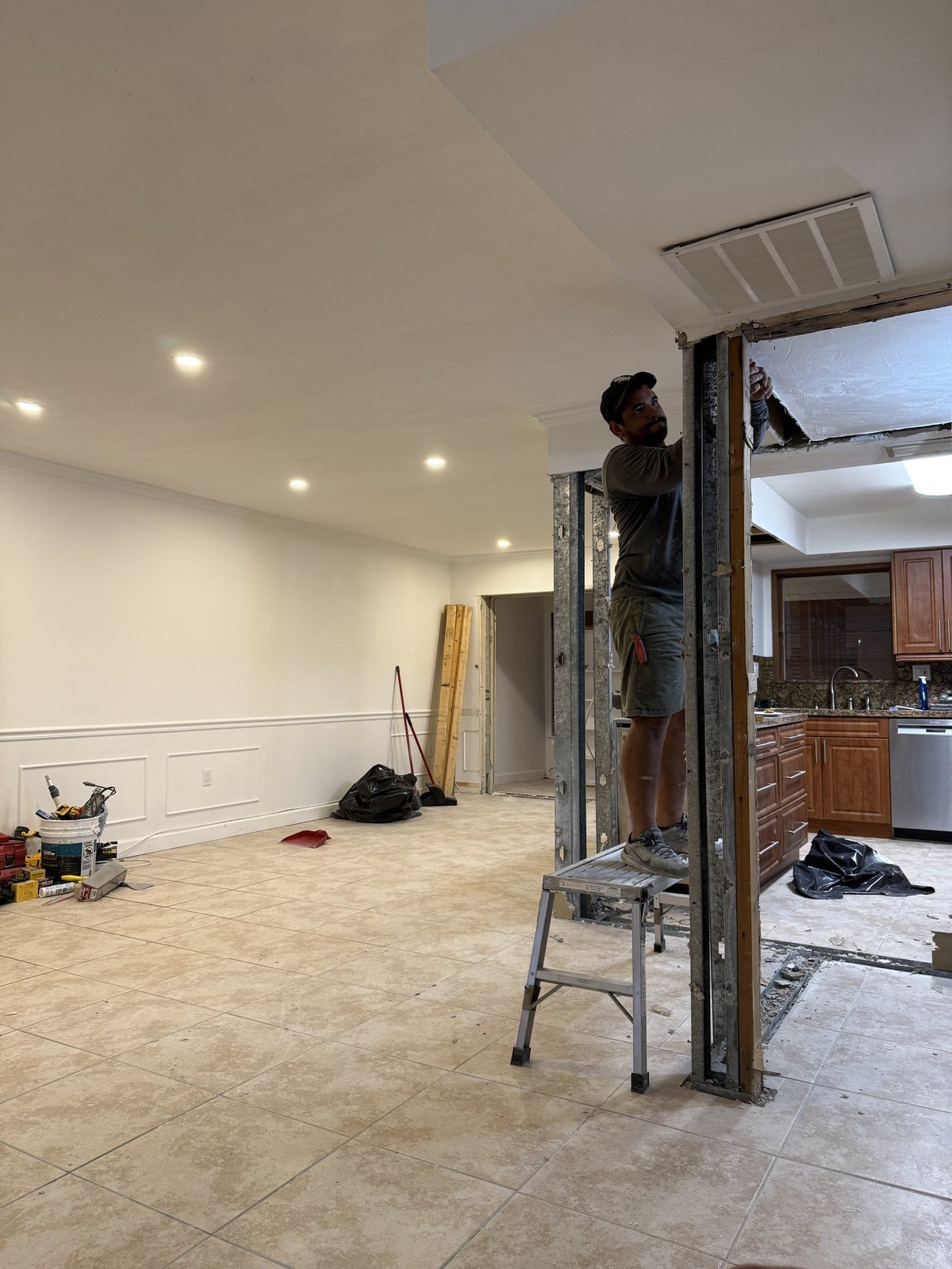 A worker on a platform at a new opening between the living area and the kitchen