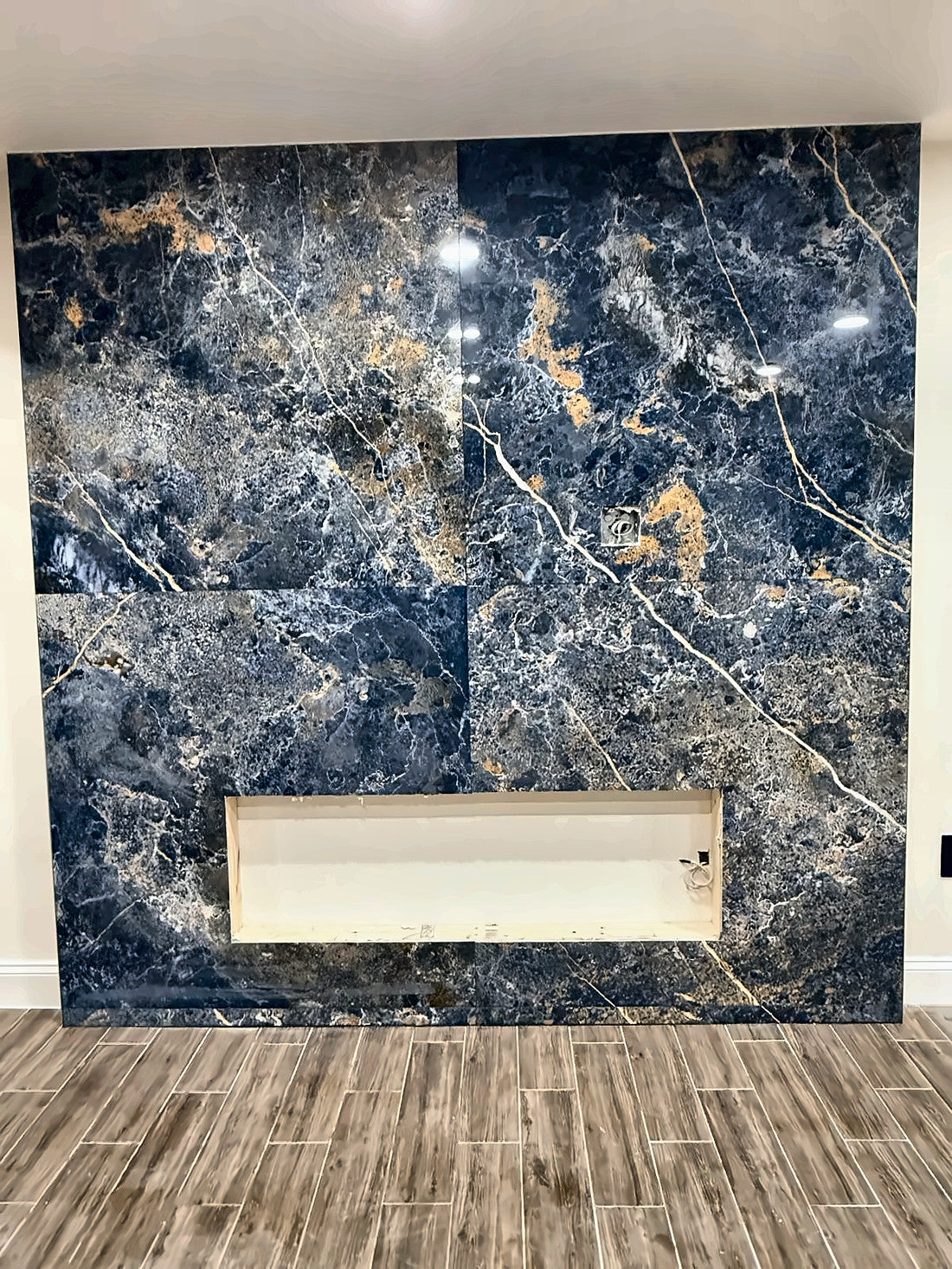 The blue and gold slab wall set floor to ceiling, the linear fireplace opening cut and framed before the unit goes in